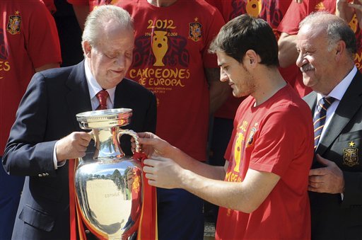 Spain's national soccer team captain Iker Casillas, centre gives the Euro 2012 trophy to Spain's King Juan Carlos, left watched by coach Vicente del Bosque, right at the Zarzuela Palace in Madrid
