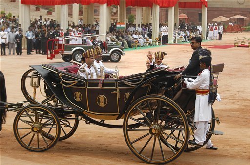 India's new President Pranab Mukherjee, in a traditional horse driven carriage, waves to the media as he arrives at the Presidential Palace, in New Delhi, India, Wednesday, July 25, 2012. Escorted by the President's bodyguards in white-uniforms, Mukherjee, 76, was sworn in Wednesday as India's 13th president in an elaborate ceremony in Parliament. (AP Photo/Manish Swarup) 
