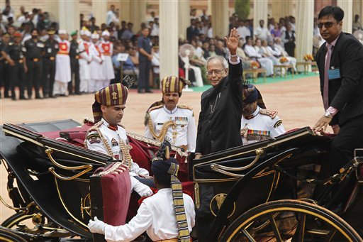 India's new President Pranab Mukherjee, in a traditional horse driven carriage, waves to the media as he arrives at the Presidential Palace, in New Delhi, India, Wednesday, July 25, 2012. Escorted by the President's bodyguards in white-uniforms, Mukherjee, 76, was sworn in Wednesday as India's 13th president in an elaborate ceremony in Parliament. (AP Photo/Manish Swarup) 
