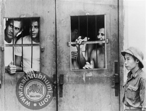 In this March 1973 file photo taken by Associated Press photographer Horst Faas, American prisoners of war look through barred wooden doors at the last detention camp at Ly Nam De Street in Hanoi, North Vietnam. Faas, a prize-winning combat photograp
