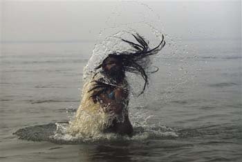 An Indian Hindu holy man, or Naga Sadhu, swings his head as he bathes at Sangam
