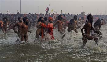 Juna Akhara Naga sadhus run to take bath at Sangam, the confluence of the Ganges, Yamuna and mythical Saraswati river, during the the first royal bath on Makar Sankranti
